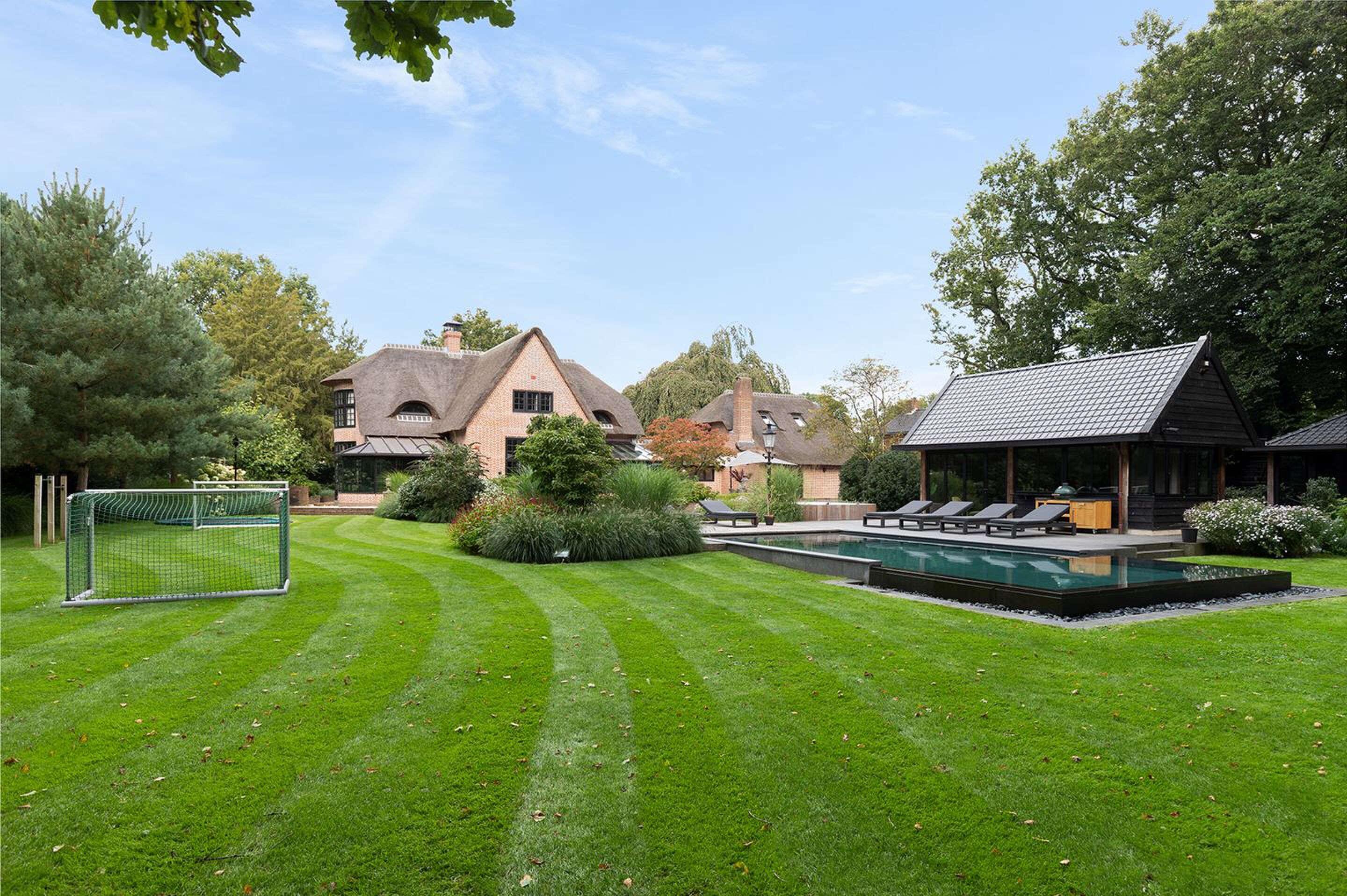 De gigantische achtertuin en het zwembad van de villa in Laren