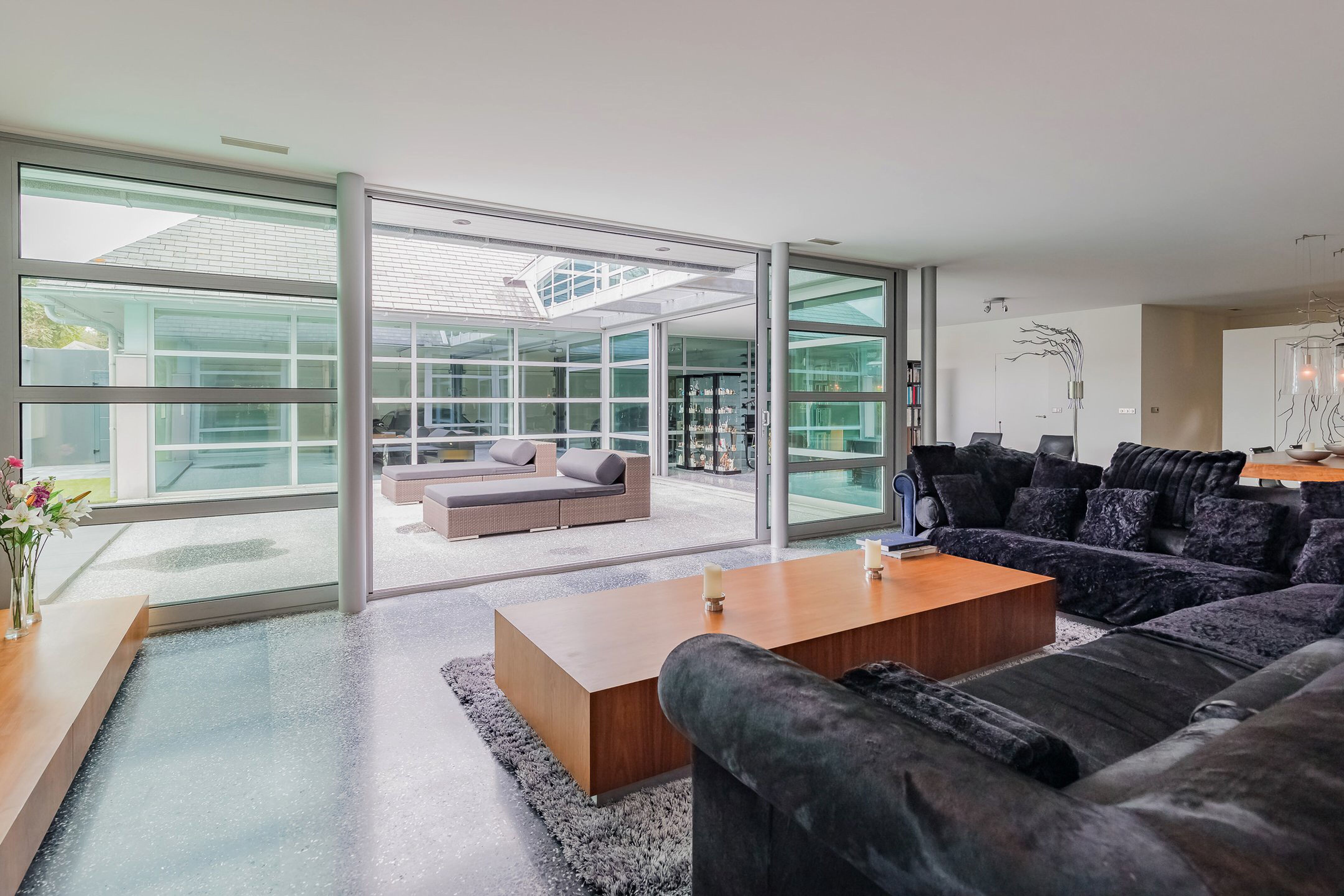 De woonkamer van de villa in Noordwijk, met een hoekbank en een houten tafel en een uitzicht op het buitenterras