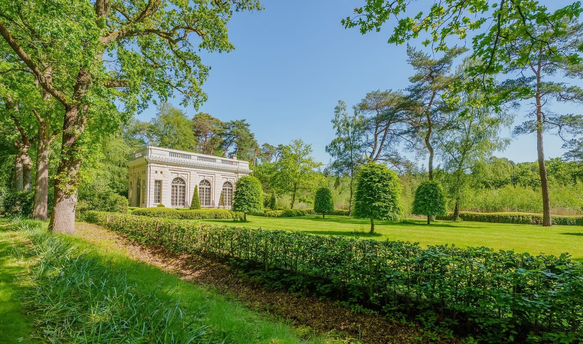 De tuin met oranjerie bij de villa in Kapellen