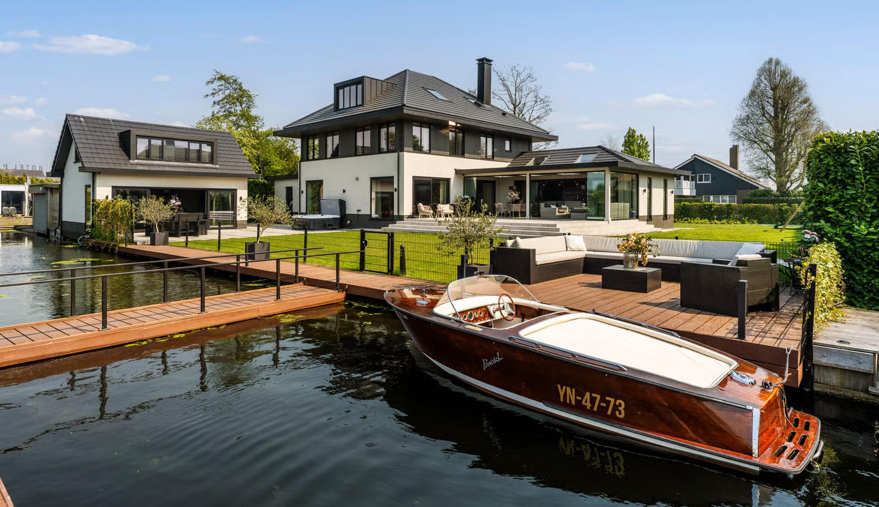 Deze waterfrontvilla met een naar een mancave omgebouwd boothuis in het weelderige Vinkeveen staat v