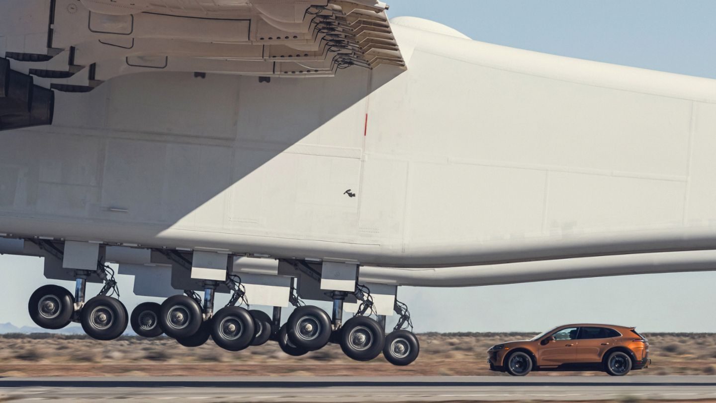 De aircraft die opstijgt voor de neus van de elektrische Cayenne