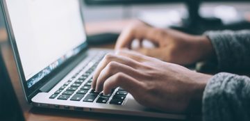 Een IT'er die op het toetsenbord van zijn laptop drukt