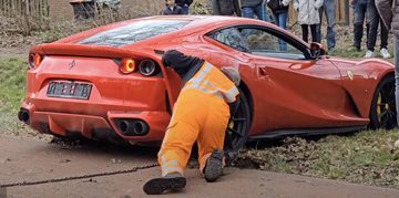 Een berger die de in een sloot belande Ferrari 812 Superfast eruit probeert te halen