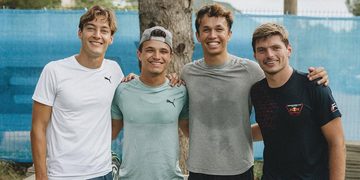 Formule 1-coureurs George Russell, Lando Norris, Alex Albon en Max Verstappen poseren voor een boom op een tropische bestemming