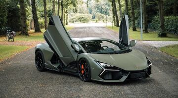 De Lamborghini Revuelto van Marktplaats met zijn vleugeldeuren open op een bospad