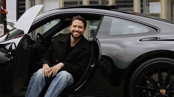 Zanger Rolf Sanchez zit met zijn benen naar buiten in zijn net nieuwe Porsche 911 Carrera T