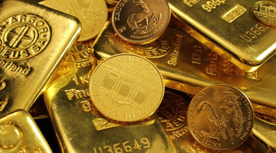 Enkele goudstaven en gouden munten, die door een aanhoudende handelsoorlog flink in prijs zijn gestegen naar een record
