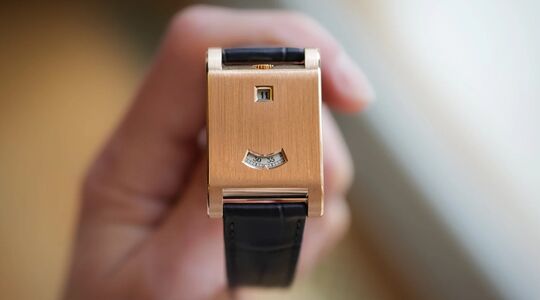 Een persoon die de Cartier Tank à Guichets vasthoudt