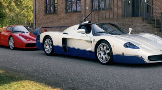 Een Maserati MC12 en een Ferrari Enzo geparkeerd voor een gebouw
