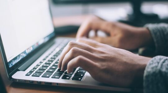 Een IT'er die op het toetsenbord van zijn laptop drukt